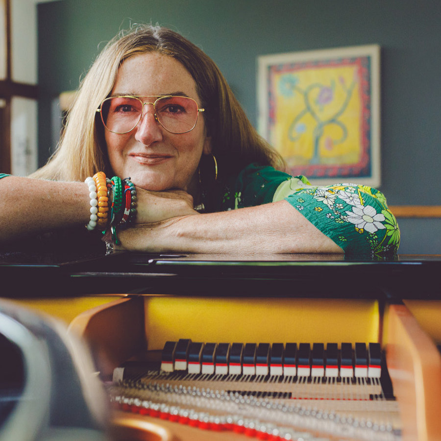 A pianist resting at a grand piano in a bright studio